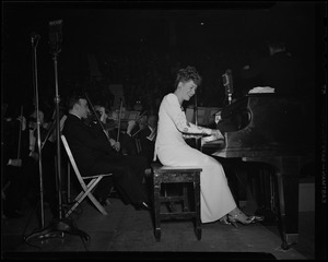 Gracie Allen playing piano with orchestra at Greater Boston United War Fund rally at Boston Garden