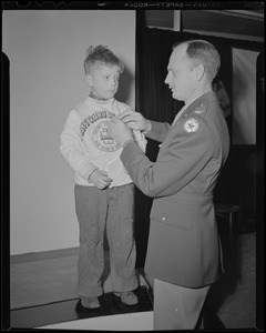 Col. George A. Ford pins Victory Volunteers badge on Boys' Clubs of Boston member at Jordan Marsh Co. Auditorium