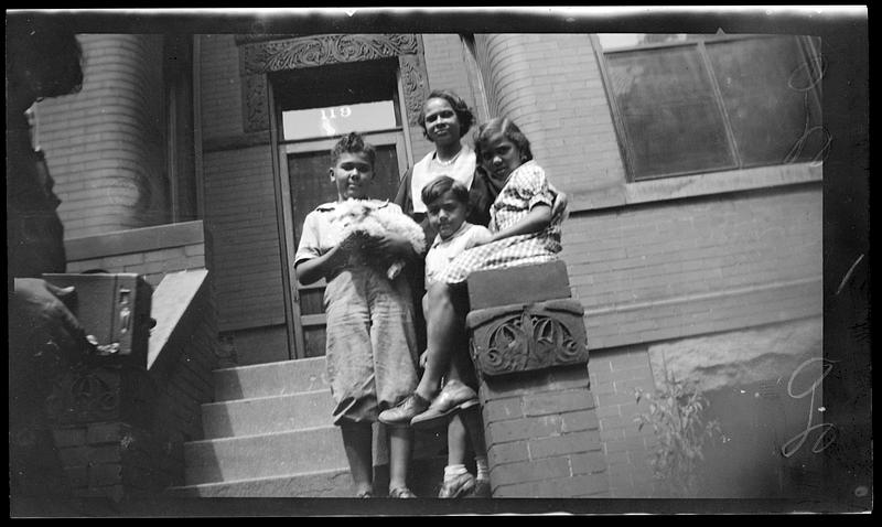 A woman and three children pose, one holding a dog