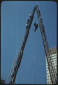 People, probably firemen, on an aerial ladder and descending down from it by rope, Boston City Hall Plaza