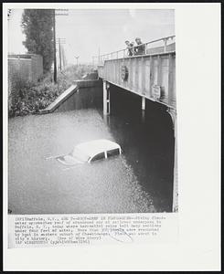 Buffalo, N.Y. -- Roof-Deep In Floodwater -- Rising floodwater approaches roof of abandoned car at railroad underpass in Buffalo, N.Y., today where torrential rains left many sections under four feet of water. More than 3000 people were evacuated by boat in eastern suburb of Cheektowaga. Flood was worst in city’s history.