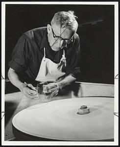 Grinding of the bowls was handled by skilled glass craftsmen. Here the crystal bowl is being worked on the grinding wheel, initial step in the finishing operation.