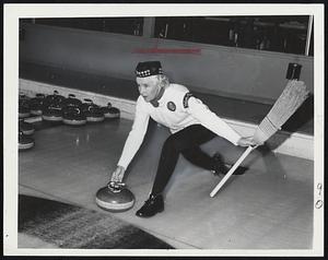 Wearing A Glengarry with her U.S.W.C.A. uniform, Helen Oleson swings a curling stone down the rink toward the goal. Official caps will be tams.