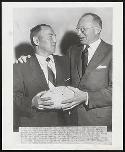 New Penn Coach - Steve Sebo, named today as head football coach at the University of Pennsylvania, accepts symbol of his trade from his predecessor, George Munger (r). Sebo, a graduate of Michigan State (1937) and backfield coach there the past three years, is the 14th man to take the Penn coaching job. Munger recently retired after 16 years as head coach to become Director of Physical Education at Penn.