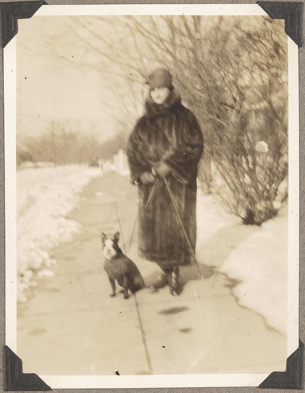 Natalie Koussevitzky in a fur coat holds the leash of a Boston terrier