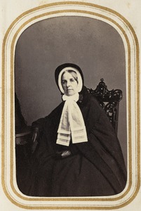 Portrait of a seated woman in coat and hat