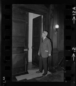 Man standing in a doorway and looking up at corner of the door frame