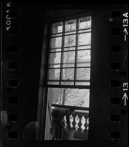 Window with broken panes and a man seen out on balcony