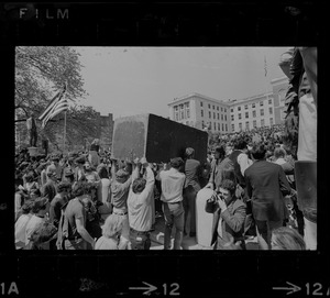 Student protesters carry a podium or platform through the crowd of Boston area college students demonstrating in the Boston Common in front of the State House to protest US march into Cambodia and the killing of four Ohio students at Kent State
