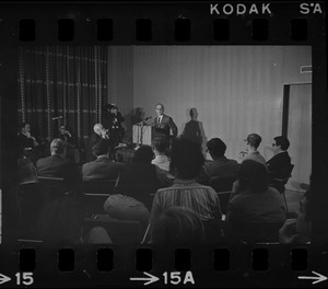 A man speaking from a podium to a roomful of people