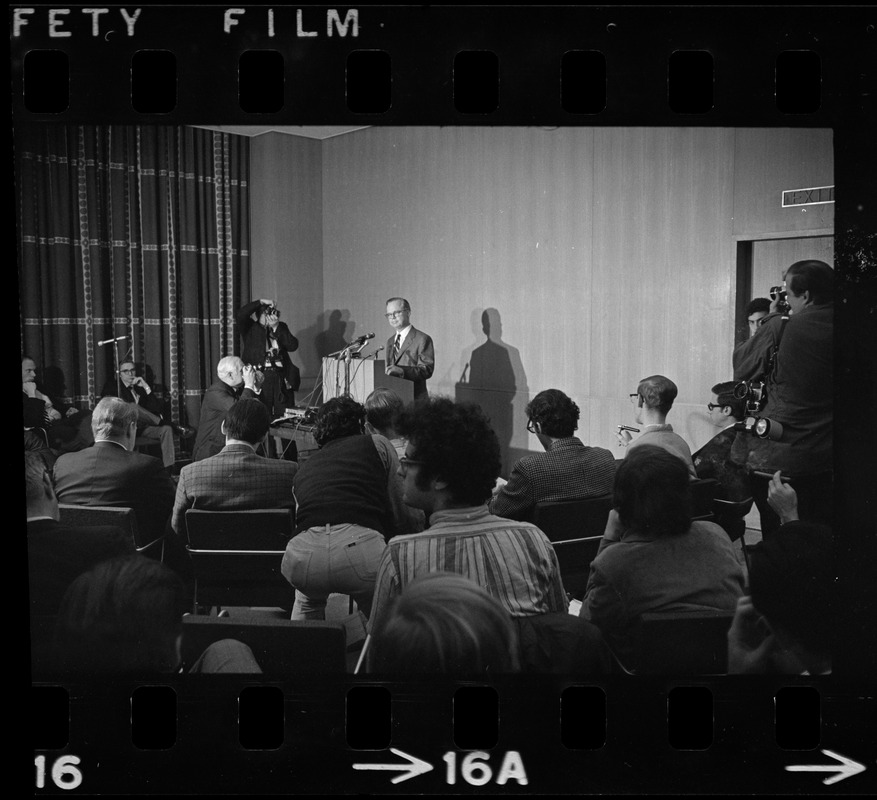 A man speaking from a podium to a roomful of people