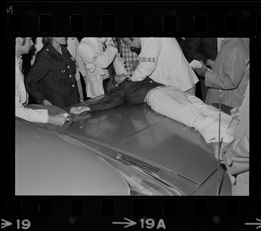 Person lying on top of vehicle hood receiving medical attention