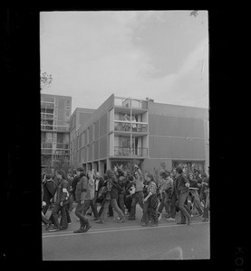 Student protesters marching past an apartment building