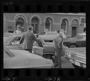 Men standing around a car on Beacon Street, near the Boston Common