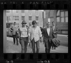 A group of men leading a man (center) across a street