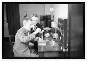 A boy sitting next to a man using an unidentified device