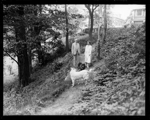 Ex Pres. and Mrs. Coolidge walking dogs on grounds of new home in Northampton