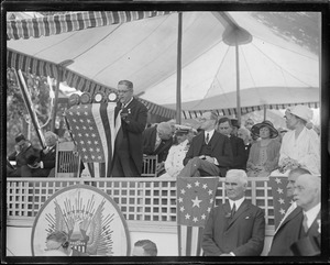 Pres. and Mrs. Coolidge seated look on while Mayor Quinn of Cambridge speaks at the podium, Cambridge