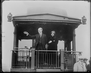 Pres. Coolidge and wife waving to crowd from back of a train