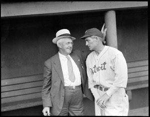 Man in suit talks with Tigers manager in Fenway dugout