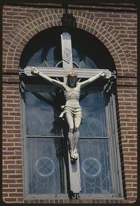 Crucifix on exterior of arched window on brick wall, Boston