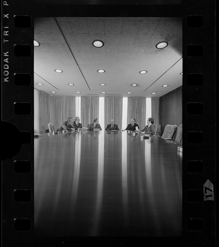 Boston Company executives meet around shiny conference table, downtown Boston