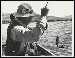 Fred Stur[?] City boats a small lake trout at Munsungun Lake in Northern