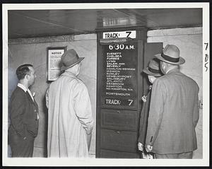 Back in Action--Spectators scan the train board at Track 7, North Station, today as it disclosed the schedule for the first train to leave on the B. & M. lines since the start of the railroad strike.