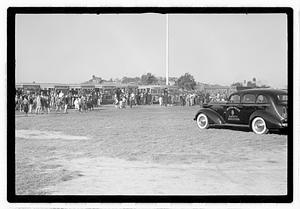 A crowd of people gathered by buses, Boston Police Safety Division car in foreground
