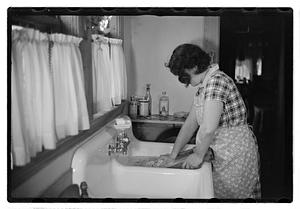 A woman doing laundry at a sink with a washboard
