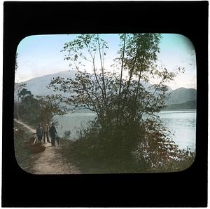 Three people walking next to a lake