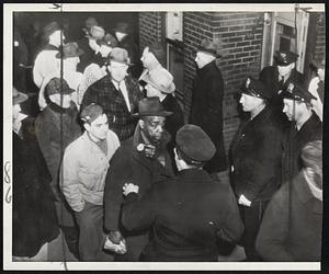 Back to Work--A worker at Wilson & Co.'s packing house in Kansas City points to his badge (center) today as a guard checks employes returning to the plant. Members of the CIO United Packinghouse Workers' Union went back to their jobs this morning following government seizure of the meat packing industry Saturday.