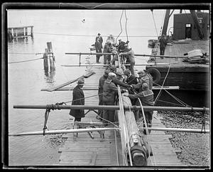 Workers tying a mast to be raised