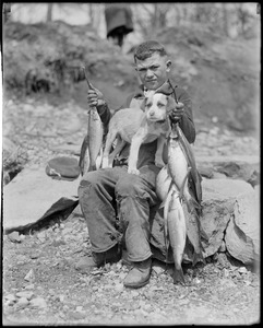 Dog on lap of seated man holding fish