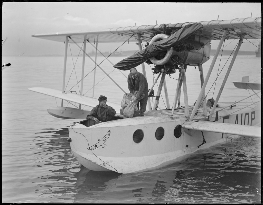 First mail by water plane lands in Boston Harbor, 1928. Radio operator Marcel Mourion of the Ilede France seaplane, which landed here yesterday afternoon, is about to disembark with two of the mail pouches. The craft reached Boston inner harbor 10 hours after...