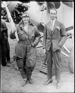 Female aviator posing in front of aeroplane