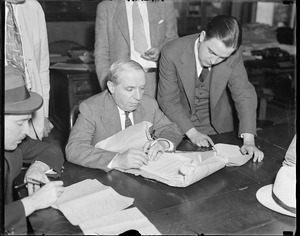 Charles Ponzi looks over documents, possibly related to deportation