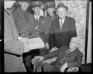 Charles Ponzi surrounded by policemen in hotel, awaiting deportation