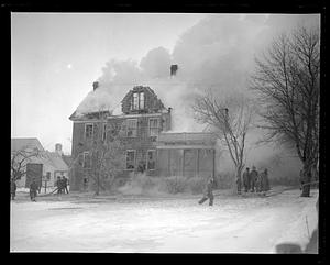 Firefighters spraying the side of a house smoking from a fire