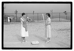 Two women holding baseball equipment