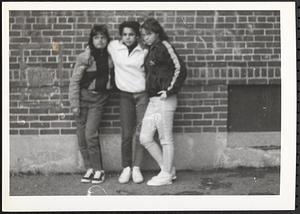 Three young women standing in front of brick wall