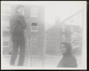 Two boys by a metal fence
