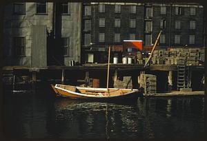 Small boat on water in front of pier and buildings