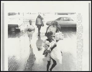 A family, with most of their necessities stuffed into pillow cases, hurries into Nicholls High School 8/17. Schools are serving as havens for families fleeing the winds and heavy rains from Hurricane Camille.