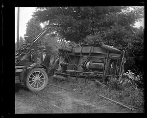 A tow truck about to tow an overturned car on its side