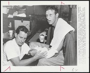 Cardinal Ace Injured--Trainer Bob Bauman applies ice pack to left wrist of St. Louis Cardinals' right fielder Stan Musial after he was hit by one if Johnny Antonelli's pitches in opener of today's doubleheader with the Giants at the Polo Grounds. Musial left game, but returned to play in nightcap.