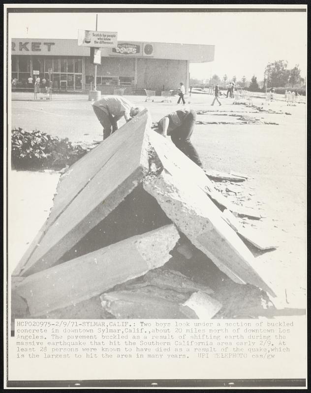 Two boys look under a section of buckles concrete in downtown Sylmar, Calif., about 20 miles north of downtown Los Angeles. The pavement buckled as a result of shifting earth during the massive earthquake that hit the Southern California area early 2/9. At least 28 persons were known to have died as a result of the quake, which is the largest to hit the area in many years.