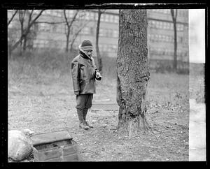 Unidentified boy, dressed for the cold, pointing at a tree
