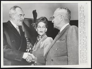 President Greets Acheson-- President Truman (right) greets Secretary if State Dean Acheson at national airport today upon Acheson's return from the big three conference in France and his visit to western Germany. Mrs. Acheson stands between them.