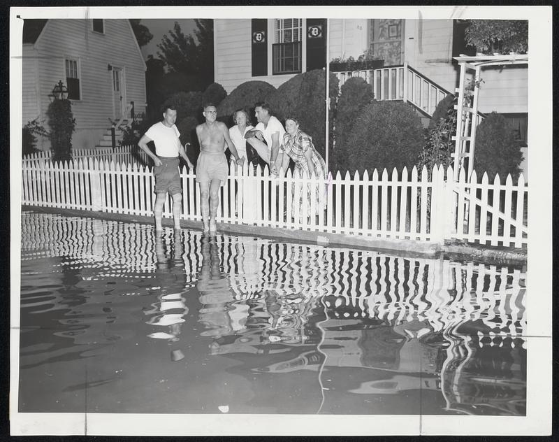 Neighboring Gossip last night in Hyde Park was all about the overflow of the Neponset river. Standing in the flood water as they talk are, left to right, Connie Donovan, John Connors, Mrs. Connors, and Mr. and Mrs. W. J. Dalton, all residents of Belnell Village.